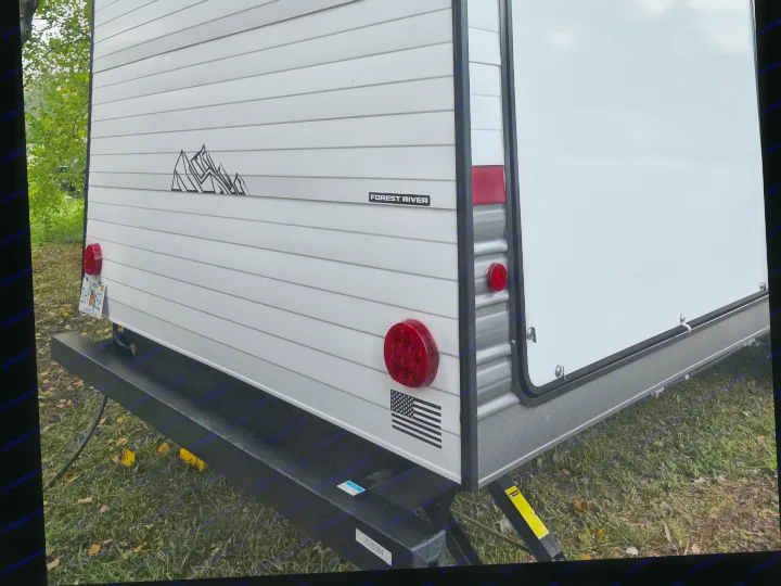 This rv rental is a white Forest River travel trailer, featuring mountain graphics, a Florida license plate, and taillights.. Forest River 29TJ 2027