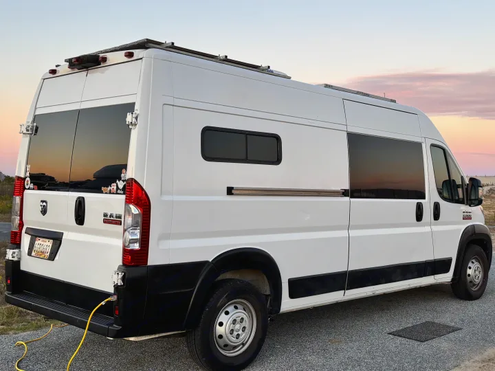 White Ram ProMaster conversion van, an RV rental, parked and connected to shore power under a beautiful sunset sky.. Ram Ram ProMaster 2500 2019
