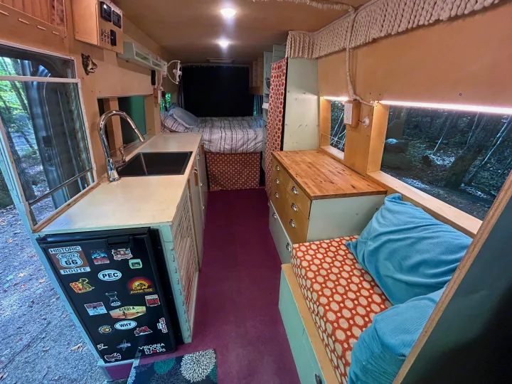 Step inside this custom RV rental interior. It features a cozy bed, kitchen area, and comfortable seating, perfect for van life adventures.. Dodge Sprinter 2005