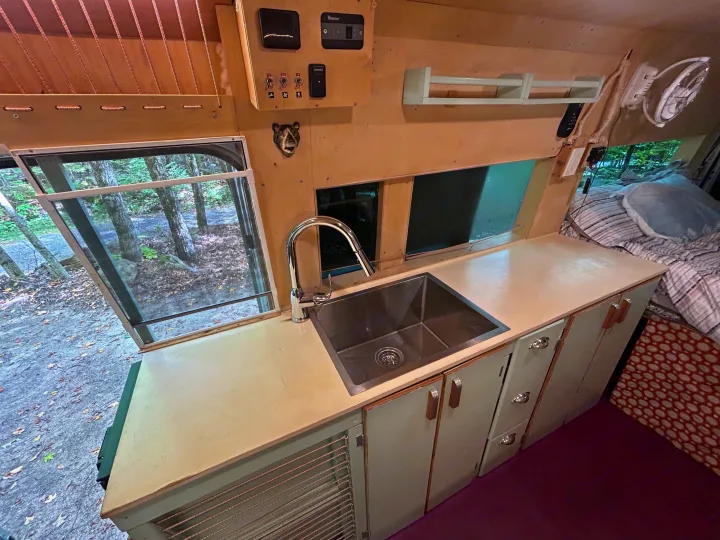 RV rental camper van interior featuring a functional kitchen with sink, counter, controls, and a window view of nature.. Dodge Sprinter 2005
