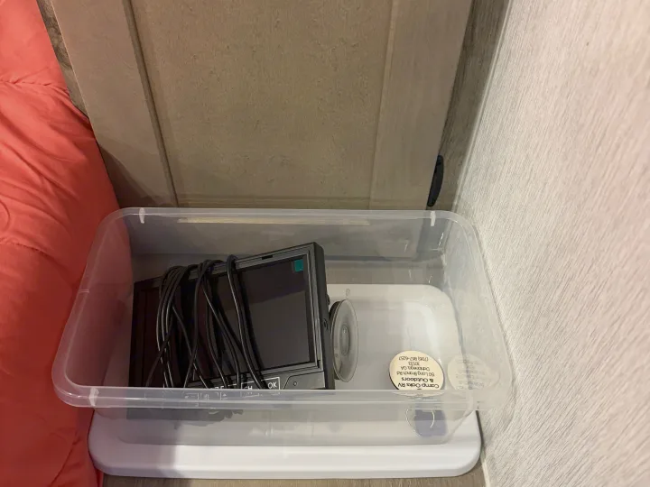 RV rental gear: Clear bin holds an RV backup camera monitor and wires, with Camp Oaks RV contact info on a sticker.. Sunlite 13BHLTD 2027