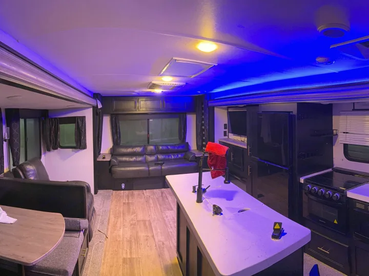 Modern rv rental interior with a spacious kitchen island, full appliances, cozy lounge, and ambient LED lighting.. Forest River Cherokee 2023
