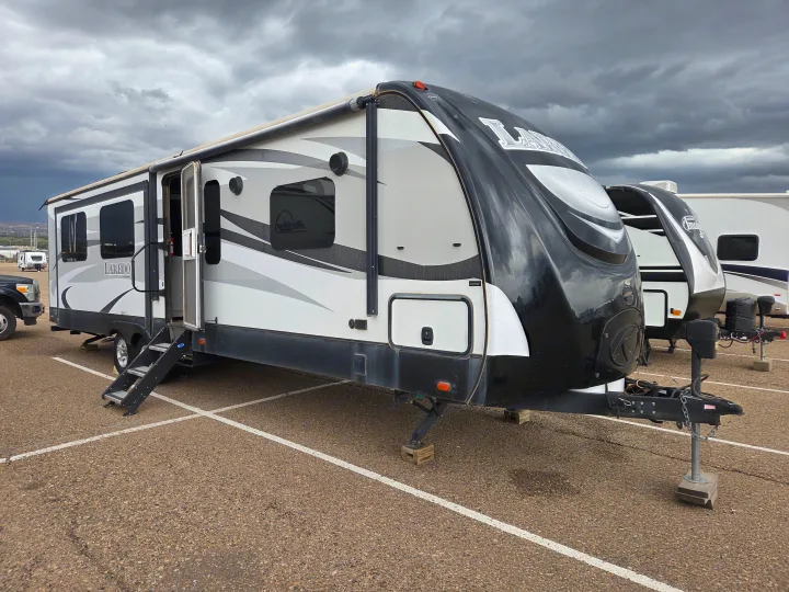 This Laredo RV rental travel trailer is parked with its steps extended under a cloudy sky, ready for adventure.. Keystone RV Laredo 2016