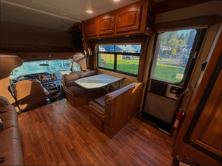 Inviting RV rental interior showcasing a bright dinette area, comfortable cockpit, and warm wood flooring. Ready for your adventure.. Jayco Greyhawk 2016