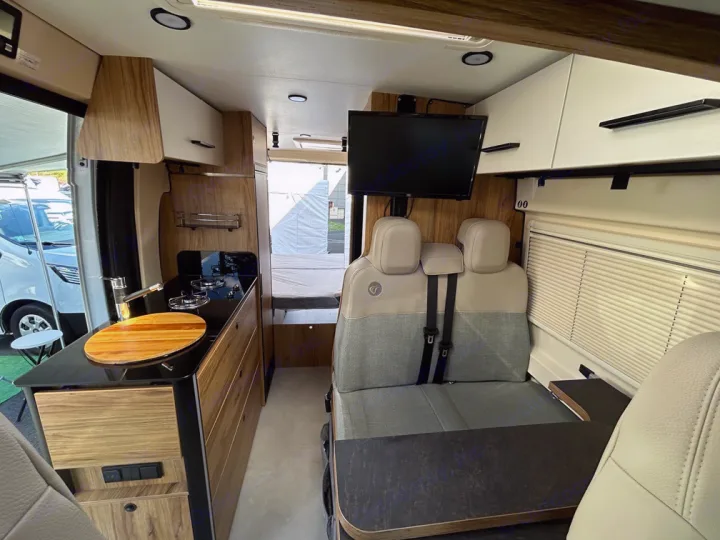 RV rental interior featuring a compact kitchen, comfortable seating, dining table, and TV for road trip adventures.. Font Vendôme Leader Camper Duo 2024