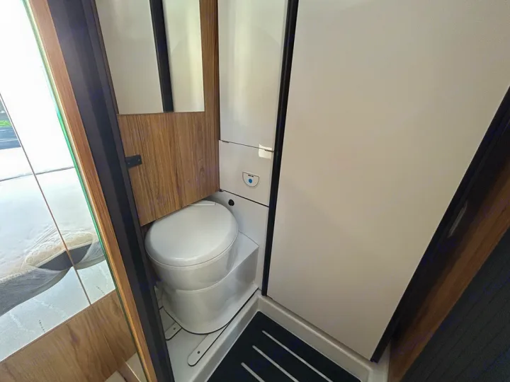 RV rental compact bathroom showing a white toilet inside a small shower stall, maximizing space for travel.. Font Vendôme Leader Camper Duo 2024