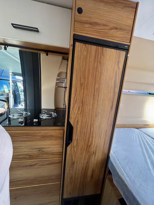 RV rental: Compact kitchen with two-burner stove, sink, and wood-paneled fridge. Bed adjacent for efficient living.. Font Vendôme Leader Camper Duo 2024