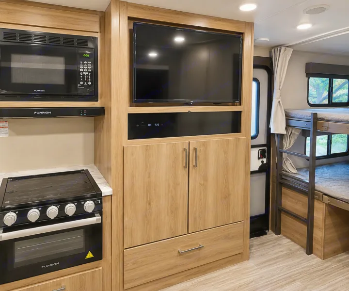 RV rental interior featuring a full kitchen with microwave & stove, entertainment area with TV, and cozy bunk beds.. Grand Design Imagine 2021