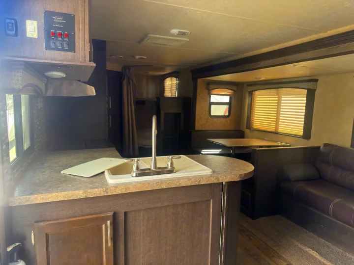 Step inside this cozy rv rental, showcasing its functional kitchen with a sink, control panel, dinette, and a glimpse of bunk beds.. Forest River 270BHS 2016
