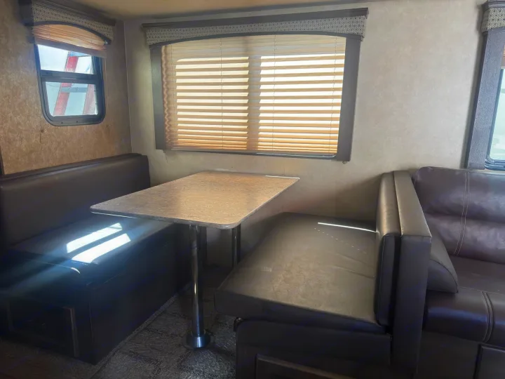 Inside an RV rental: a comfortable dinette with dark brown booth seats and a table, lit by natural light.. Forest River 270BHS 2016
