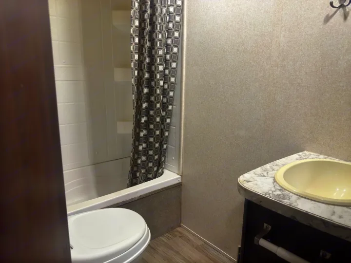 Functional bathroom in an RV rental, featuring a tub/shower, toilet, and sink. Compact and ready for your travels.. Jayco Jay Feather 2018
