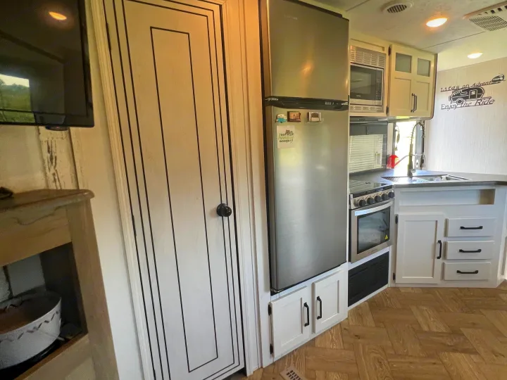 Explore this modern RV rental's kitchen, featuring a full-size fridge, stove, microwave, and ample storage.. Forest River Palomino Puma 2021