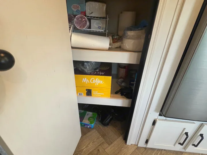 Compact RV rental pantry stocked with paper goods, a Mr. Coffee coffeemaker box, and other kitchen supplies on shelves.. Forest River Palomino Puma 2021