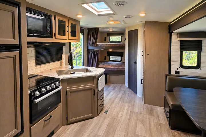 Modern rv rental with a bright kitchen, full bunk beds, and a cozy dinette, featuring light wood cabinetry.. Jayco White Hawk 2022