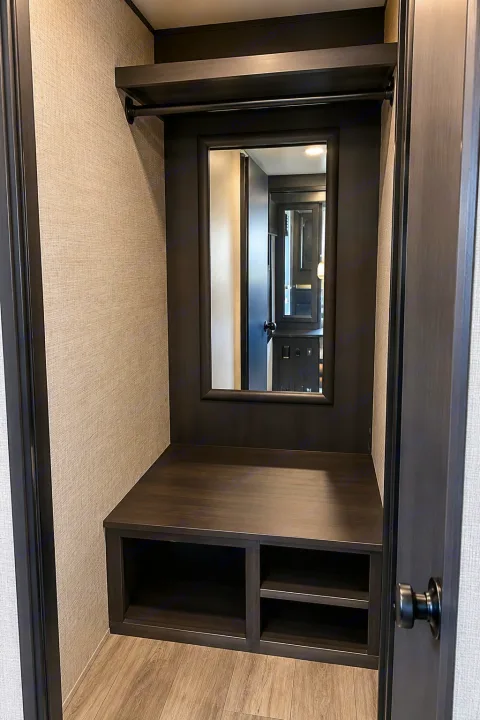 RV rental interior: a dark wood closet/entryway with an integrated mirror, top shelf, hanging rod, bench seating, and lower storage shelves.. Jayco White Hawk 2022