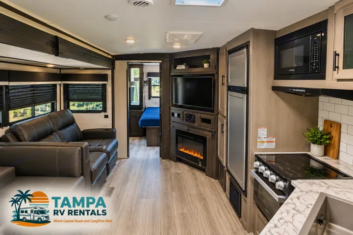 Spacious RV rental interior featuring a living area with recliners, entertainment center with fireplace, full kitchen, and bedroom.. Jayco White Hawk 2022