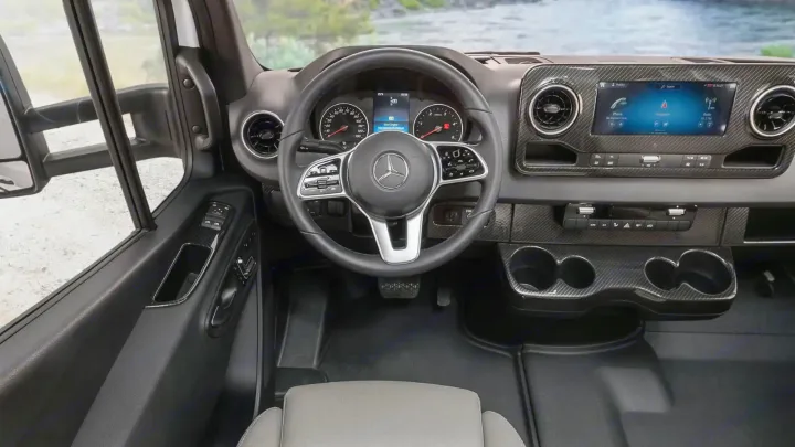 The spacious driver's cockpit of a modern Mercedes-Benz Sprinter RV rental, showcasing its dashboard, infotainment, and controls.. Winnebago Navion 2023