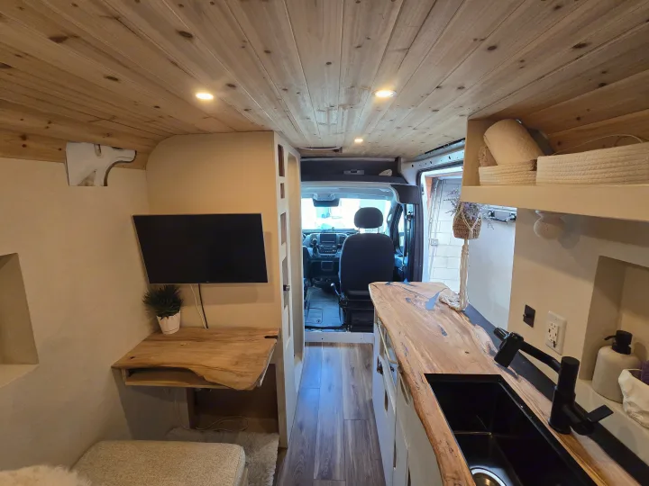 Explore this unique RV rental: a stylish van conversion with a rustic wood ceiling, kitchenette, and dedicated workspace.. Dodge 1500 2023