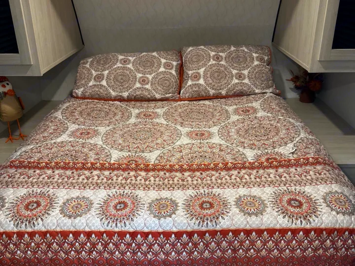Cozy RV rental bedroom featuring a comfy bed with an intricate, earthy-toned mandala quilt design.. Forest River Palomino Puma Camping Edition 2025