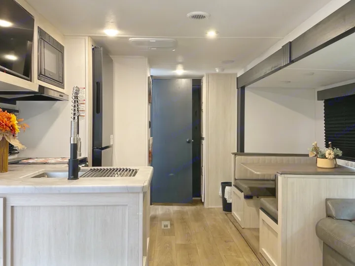 Modern rv rental interior: kitchen island with sink, dining booth, and living area, complete with fall decorations.. Forest River Palomino Puma Camping Edition 2025