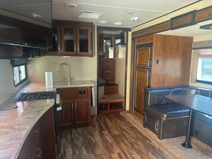 Spacious RV rental interior with a fully equipped kitchen, dining dinette, large refrigerator, TV, and steps leading to a sleeping area.. Grand Design Reflection 2019
