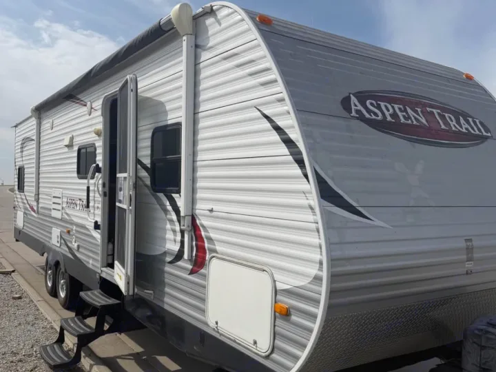 Aspen Trail RV rental. This travel trailer, with its door open and steps down, is parked outdoors.. Aspen Trail Aspen Trail Trailer 2014