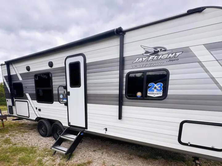 Explore the side view of this Jayco Jay Flight RV rental, a white and grey travel trailer with a 2+3 year warranty.. Jayco Jay Flight 2027