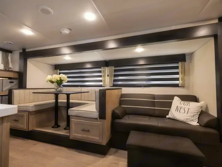 This modern RV rental interior features a cozy U-shaped dinette with a table, comfortable sofa, and practical storage.. Forest River Cherokee Grey Wolf 2026