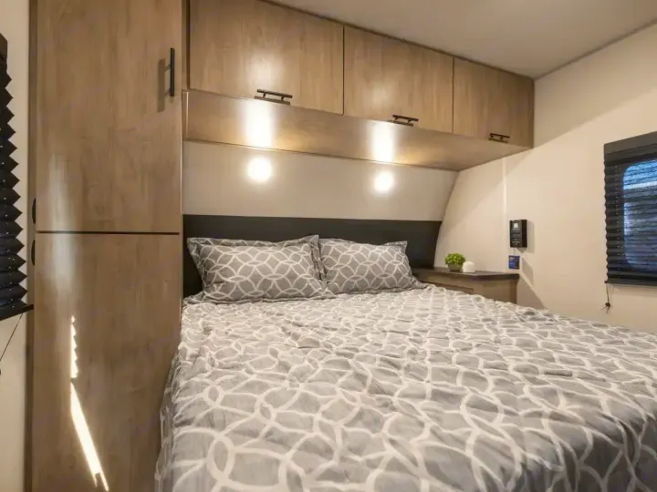 Comfortable RV rental bedroom featuring a bed with geometric bedding, overhead storage, and integrated lighting for cozy travels.. Forest River Cherokee Grey Wolf 2026