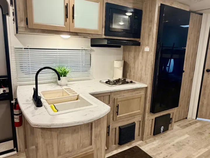 RV rental kitchen: modern design with sink, microwave, stovetop, and fridge, ready for comfortable travel.. Gulf Stream Enlighten SE 2025