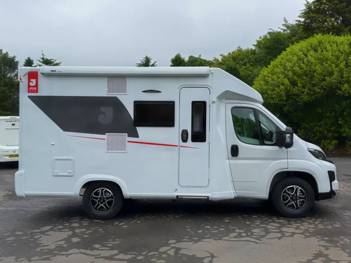 Modern white Joa campervan, perfect for rv rental adventures. This side view shows its sleek design, parked with trees behind.. JOA 60F 2027