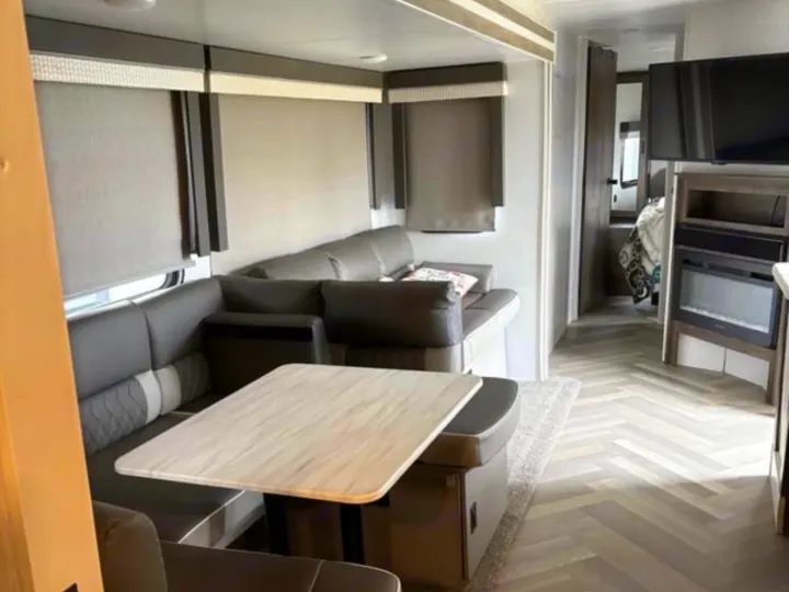Bright rv rental living area with a U-shaped dinette, sofa, TV, and electric fireplace. Modern travel trailer.. Forest River Salem 2022