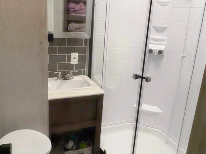 Compact RV rental bathroom with shower, sink, vanity, and toilet. Ideal for travel accommodation.. Forest River Salem 2022