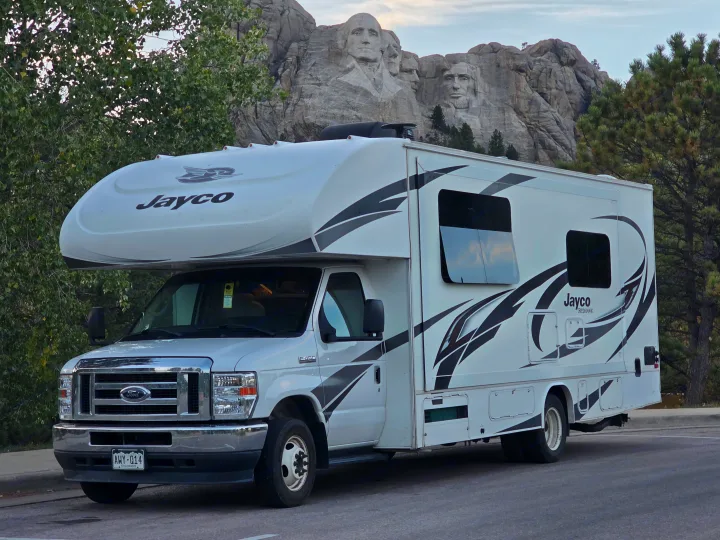 An RV rental (Jayco motorhome) parked in front of Mount Rushmore National Memorial, featuring the carved presidents.. Jayco Redhawk 2021