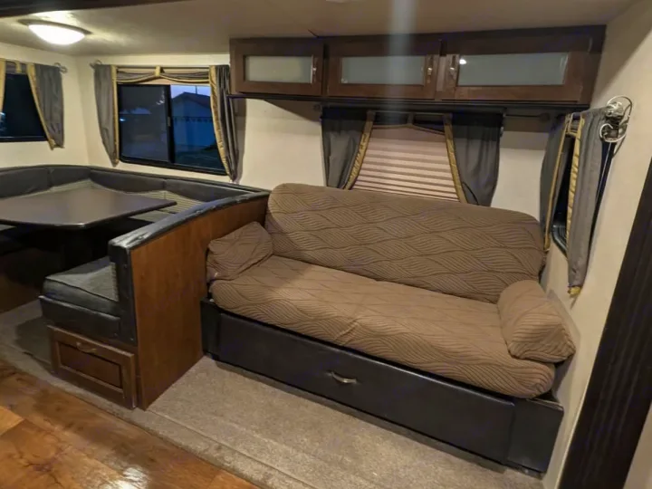 RV rental interior features a U-shaped dinette on the left and a pull-out sofa with under-storage on the right, under overhead cabinets.. Forest River Salem 2017
