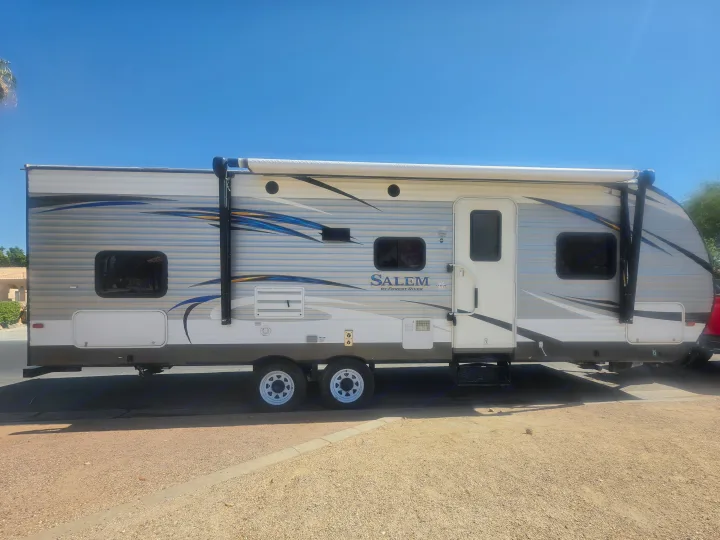 A white and grey Salem rv rental travel trailer with blue graphics and a rolled-up awning, ready for adventure.. Forest River Salem 2017