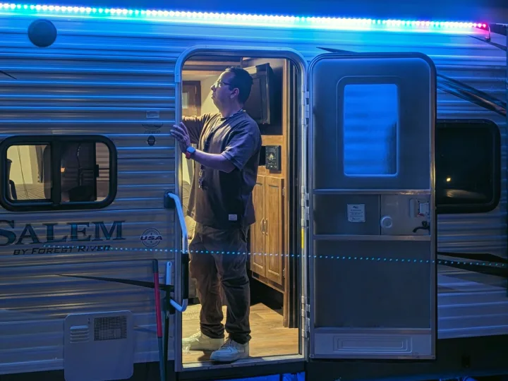 Man in the doorway of an RV rental, illuminated by bright blue LEDs, with the interior visible.. Forest River Salem 2017