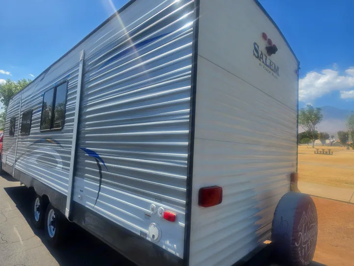 Side and rear view of a Salem by Forest River travel trailer rv rental, parked under a blue sky.. Forest River Salem 2017