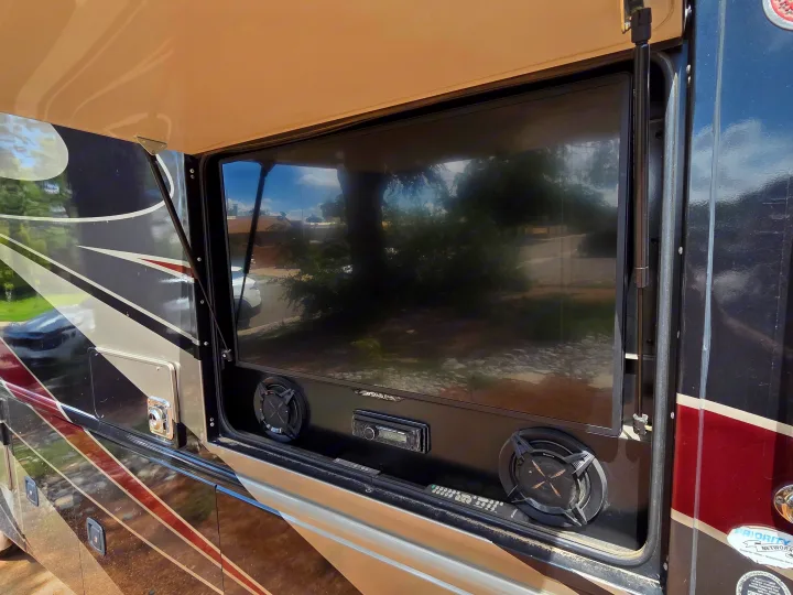 Outdoor entertainment on an RV rental: a large TV, speakers, and stereo unit visible in an open compartment.. Holiday Rambler Vacationer 2019