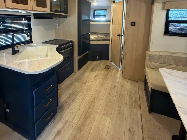 Clean rv rental interior featuring a modern kitchen with dark cabinets, bunk beds, and a dinette area for comfortable travel.. Avenger Avenger Trailer 2026