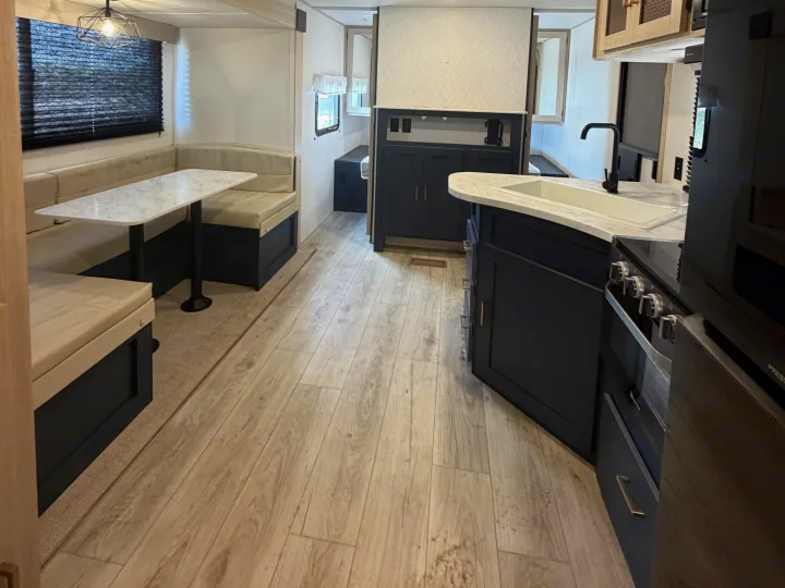 Spacious RV rental interior featuring a modern kitchen with a sink, dark cabinetry, and a U-shaped dinette area.. Avenger Avenger Trailer 2026