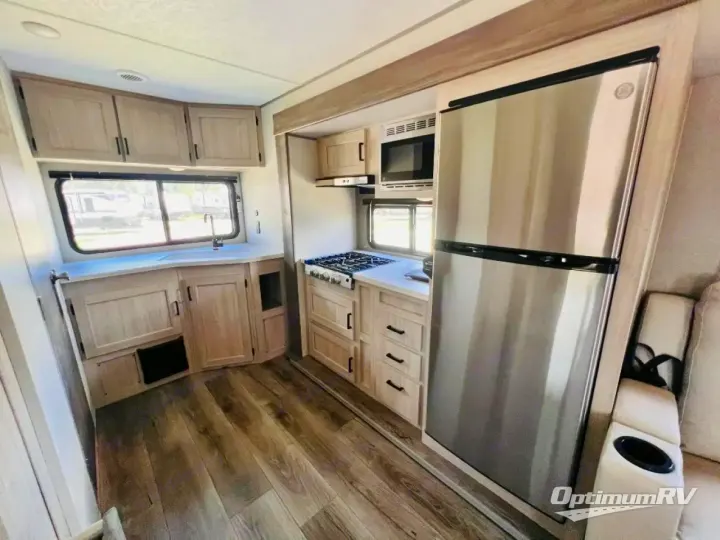 Bright RV rental interior showing a full kitchen with stainless steel appliances, sink, stovetop, and comfortable seating.. Coachmen Catalina Summit 2024