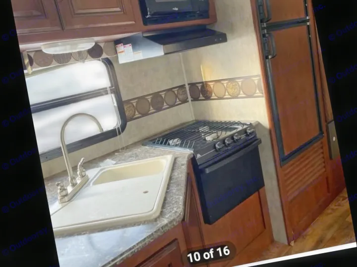 Compact kitchen in an RV rental, featuring a sink, stove/oven, microwave, and refrigerator.. Keystone RV Passport Ultra Lite 2015