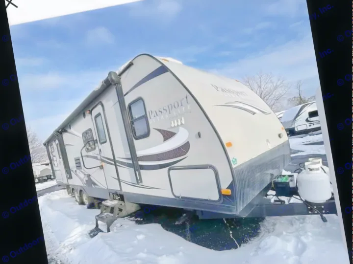 A large, light-colored travel trailer (Passport Ultra Lite) sits in snow. Perfect for an RV rental or winter camping adventure.. Keystone RV Passport Ultra Lite 2015