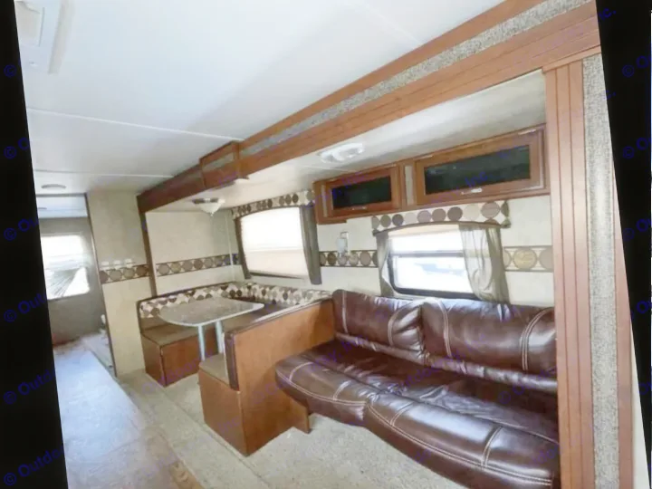 RV rental interior: spacious living area with brown sofa, dinette, and overhead cabinets.. Keystone RV Passport Ultra Lite 2015