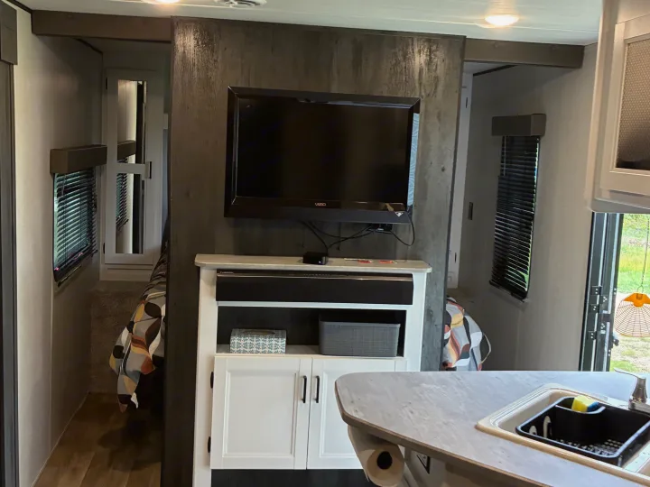 Inside a comfortable RV rental: entertainment center, kitchen with sink, and a view into the sleeping area.. Keystone RV Hideout 2022
