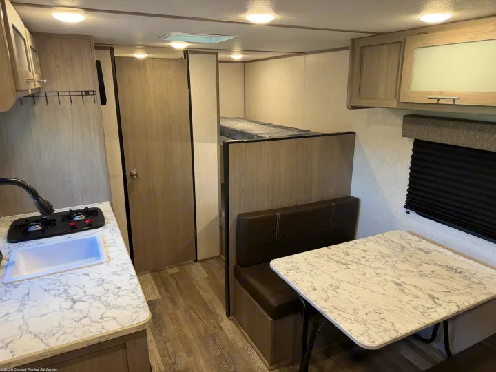 Modern RV rental interior features a compact kitchen, dining area, and cozy bunk beds.. Coleman Lantern 17b 2023