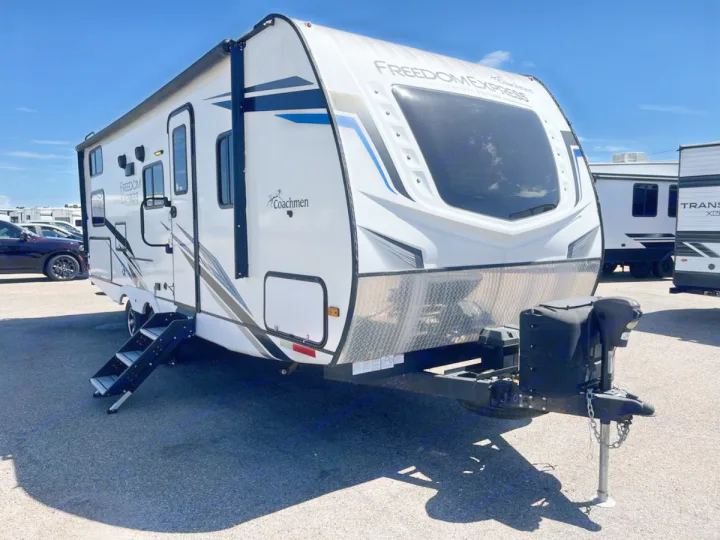 This white Coachmen Freedom Express travel trailer, with extended steps and hitch visible, is perfect for an RV rental adventure.. Coachmen Freedom Express 2022
