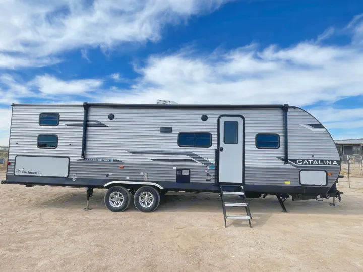 Coachmen Catalina Legacy Edition RV rental travel trailer, parked on dirt under a blue sky.. Coachmen Catalina Legacy Edition 2024