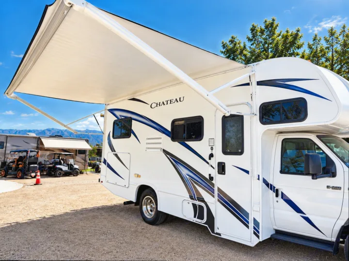 Sunny RV rental: a Chateau motorhome with its awning extended at a scenic campground, perfect for outdoor adventures.. Thor Chateau 2020